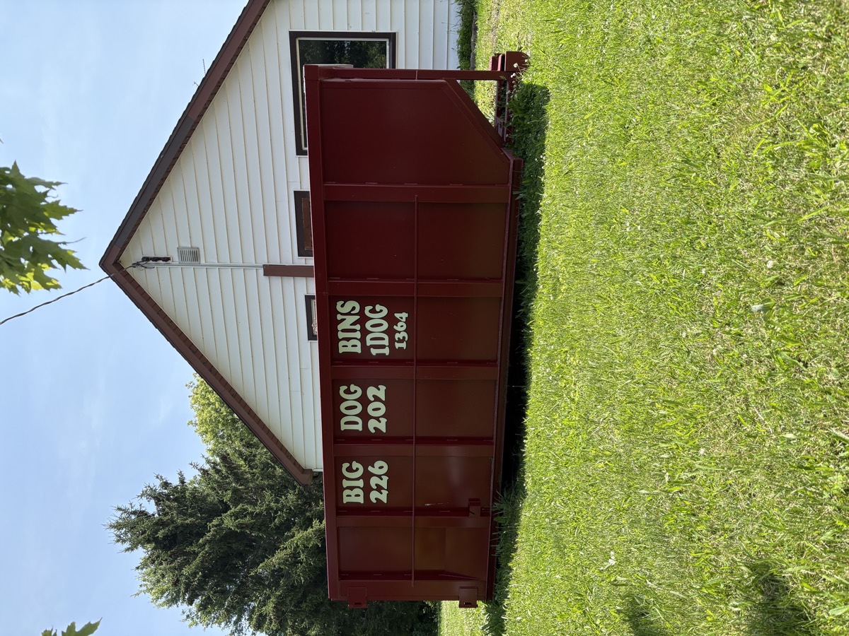 A Big Dog Bins bin sitting neatly on the grass beside a house at a residential job.